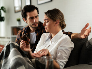 Young woman sick in bed. .Woman drinking medicine, having stomach pain. Husband comforts his wife..