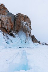Fototapeta na wymiar Lake Baikal in winter day. High cliffs on Olkhon Island. Large beautiful blocks of ice cover the foothills of the mountains.