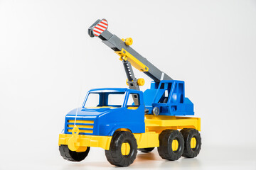 Plastic car. Toy model isolated on a white background. Yellow-blue truck crane with an arrow to lift the load.