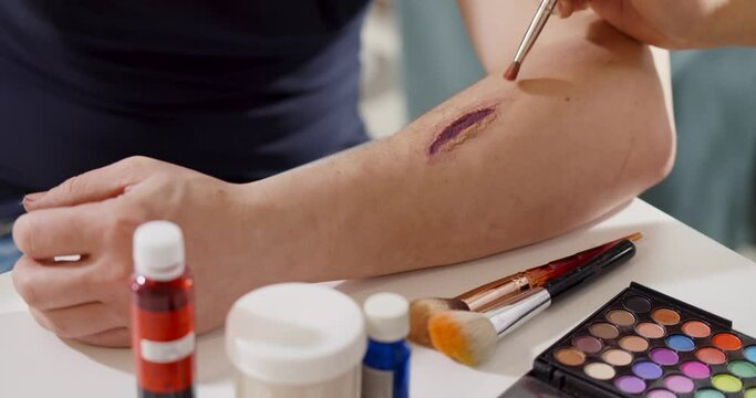 Close up of professional making fake wound makeup special effect on arm