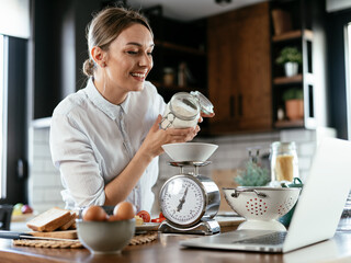 Young woman in kitchen. Beautiful woman following recipe and cooking..