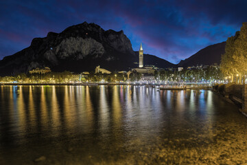 Fototapeta premium Famous holiday resort on Lake Como, Italy. City of Lecco at dusk with the lights of the promenade reflected on the lake 