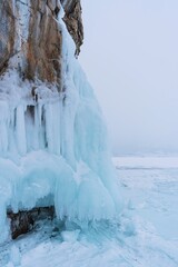 Lake Baikal in winter day. High cliffs on Olkhon Island. Large beautiful blocks of ice cover the foothills of the mountains.