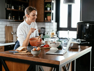 Young woman in kitchen. Beautiful woman following recipe and cooking..