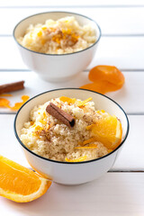 Delicious homemade couscous with oranges and cinnamon on rustic wooden background. Tasty vegan food.