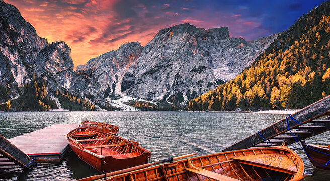 Spectarcular famous place with typical wooden boats on the alpine lake Braies in Dolomites. Impressive Lago di Braies during sunset. Amazing Autumn nature landscape. Iconic location for photographers