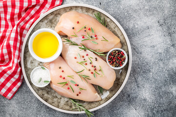 Chicken fillet with herbs and spices on gray table flat lay. Chicken meat with ingredients for cooking. Top view.