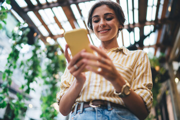 Smiling young ethnic lady using smartphone in cafe - Powered by Adobe