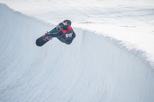 People are enjoying half-pipe skiing / snowboarding	