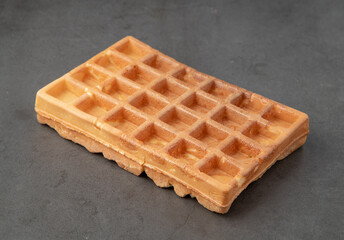 Single Belgian waffle on a dark stone background.