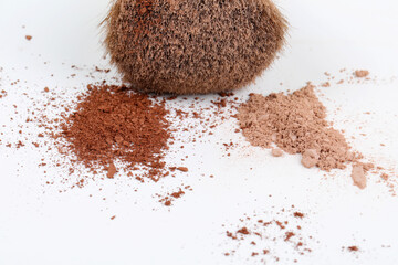 Scattered two color tan facial loose powder and make-up brush isolated on white background. Copy space.