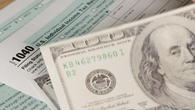 Dallar bills and Tax day. 1040 form ready to be filled and returned.
