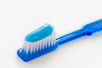 close-up of a blue toothbrush with toothpaste isolated over white
