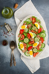 Delicious salad with tuna, fresh vegetables (lettuce, tomatoes, cucumbers), eggs with a dressing of olive oil, lemon juice and freshly ground pepper. Mediterranean cuisine. Nicoise. Selective Focus
