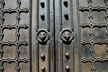 Аntique doors made of metal with a pattern of intertwined crosses and heads of lions