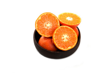 Whole and slice juicy fresh orange fruits in a wooden bowl