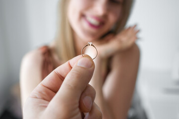 A man holds a wedding ring in his hand against the background of a happy woman.The concept of engagement, marriage proposals and newlyweds