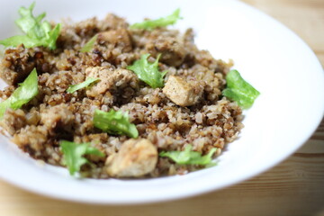 Buckwheat with meat and salad in white plate on wooden background