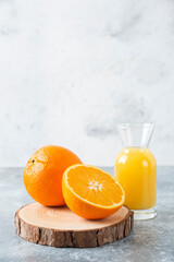 Glass pitcher of juice with sliced orange fruit on a wooden board