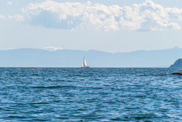 Ocean view with mountains, small island, blue sky and white clouds at summer day.