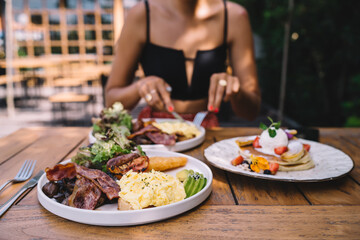 Crop unrecognizable woman enjoying tasty breakfast on terrace