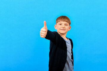 The boy shows a thumb up on a blue background.