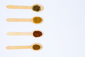 Various spice seeds in wooden spoons on a white background. Seeds of beet, mustard, lettuce, arugula, on a white background. Place for an inscription. View from above.