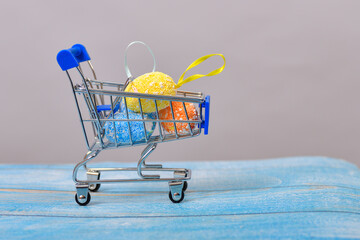 Easter eggs in a grocery cart on a wooden background.