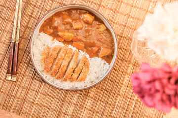 Top view Japanese curry rice topping with fried pork and vegetables in white and black plate with chopsticks. Curry rice Japanese food.