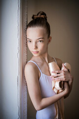 young slender ballerina in white tutu dances on pointe shoes in a spacious, bright room with large windows. © Maria Moroz