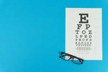 Glasses and a vision test table on the right on a blue background