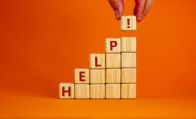 Support and help symbol. Pyramid from wooden cubes with the word 'help'. Businessman hand. Business, psychology, support and help concept. Beautiful orange background, copy space.