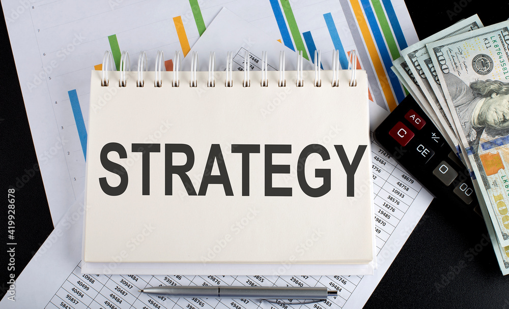 Poster strategy text written on the notebook with chart,calculator and dollars