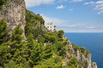 Fototapeta na wymiar Traditional italian house situated on a cliff. Landscape view with trees and cliffs and a fantastic view of the Tyrrhenian Sea in Capri Island, Italy