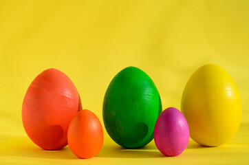A row of colorful Easter eggs on yellow background with shadow and copy space.