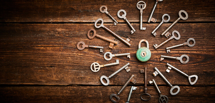 Vintage rusty padlock surrounded by group of old keys on a weathered wooden background. Internet security and data protection concept, blockchain and cybersecurity. Lockdown.  Escape route and room