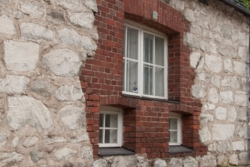 Fototapeta na wymiar Одно большое и два маленьких окна в стене из красного кирпича и белого камня.