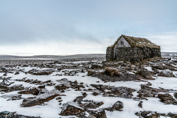 remote stone and moss roofed house in the highlands of Iceland. Snow and rock ground surrounding this seemingly endless destitute landscape
