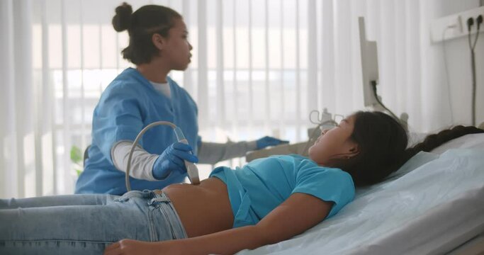 Doctor making abdominal ultrasound for asian child girl using scanner machine
