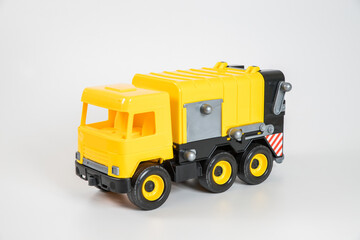 Fototapeta na wymiar Plastic car. Toy model isolated on a white background. Yellow truck for the transport of garbage.