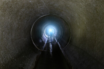 Flooded round sewer tunnel with flowing sewage