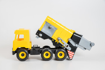 Plastic car. Toy model isolated on a white background. Yellow truck for the transport of garbage.