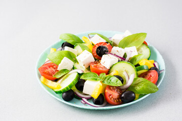 Fresh homemade greek salad with basil leaves on a plate on the table. Domestic life