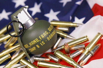 M67 frag grenade and many yellow bullets and cartridges on United States flag. Concept of gun...