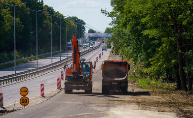 Two special trucks drive along road under construction. Road to be paved with asphalt. Selective...