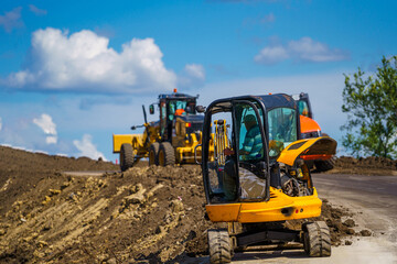 Yellow backhoe with hydraulic piston arm. Heavy machine for excavation in construction site.