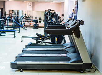 Modern gym interior with equipment. Fitness club with row of treadmills for fitness and cardio...