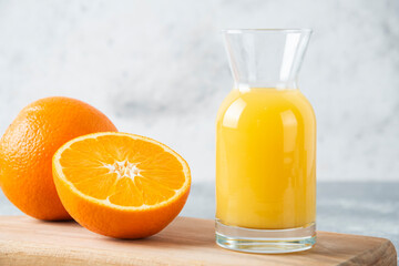 Glass pitcher of juice with sliced orange fruit on a wooden board