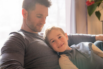 father and son sit on the sofa at home