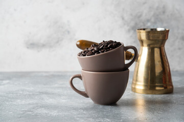 Cup full of coffee beans and coffee maker on marble background